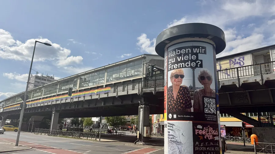 Digitale Litfaßsäule an einem Berliner S-Bahnhof mit der Kodex-Frage: Haben wir zu viele Fremde?